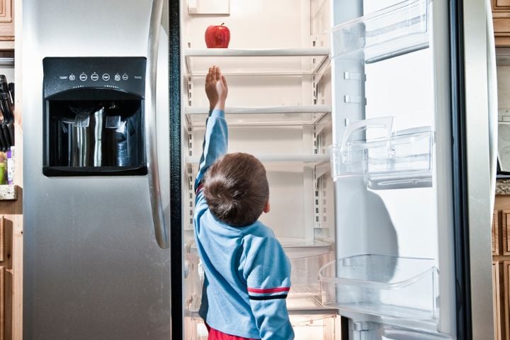 child reaching for apple on top shelf in fridge