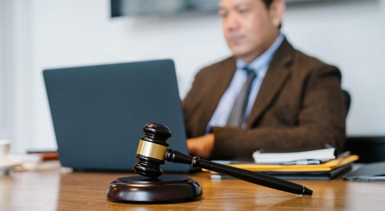 lawyer at laptop behind a gavel