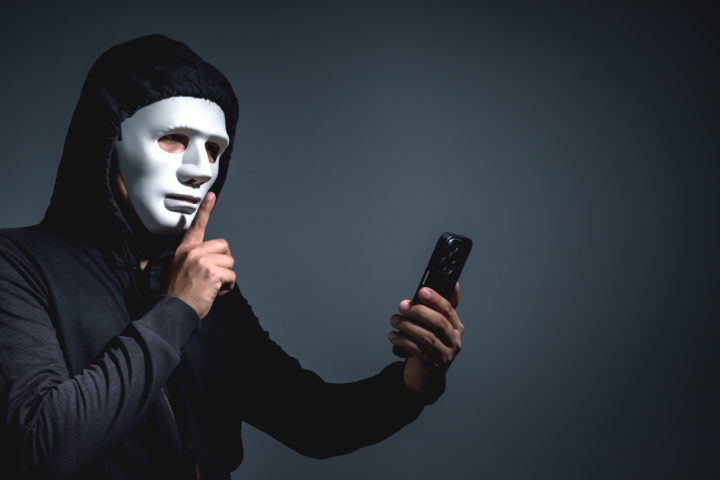 man with mask shushing his phone