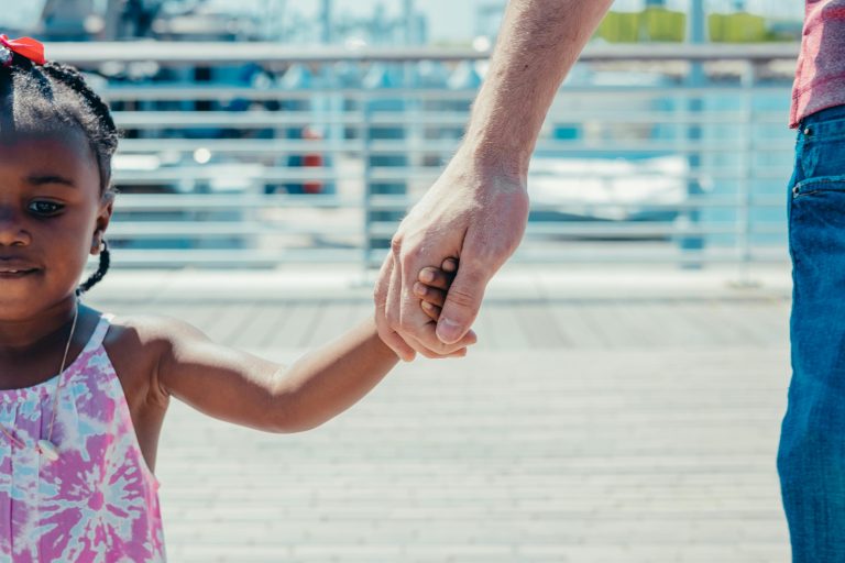 little girl holding the hand of an adult