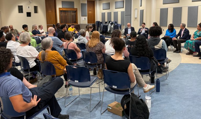 A number of people seated watching a candidate forum