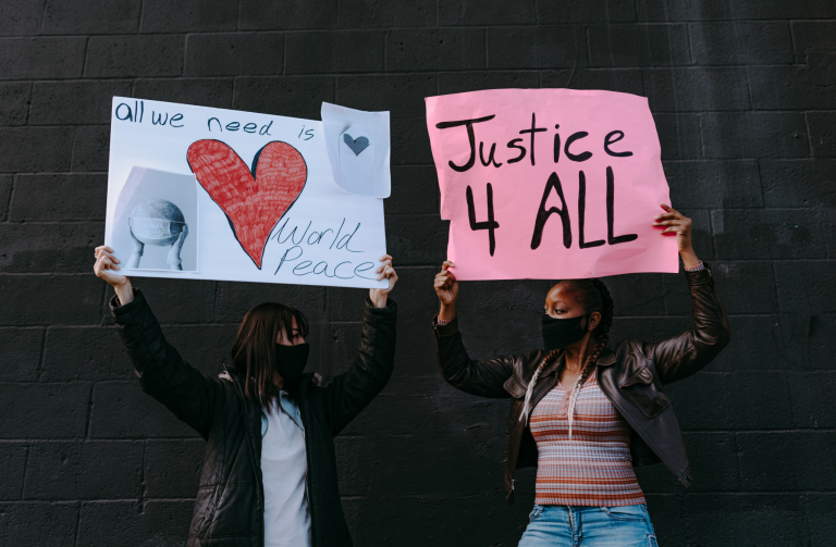 two protesters with masks holding Justice 4 All protest signs