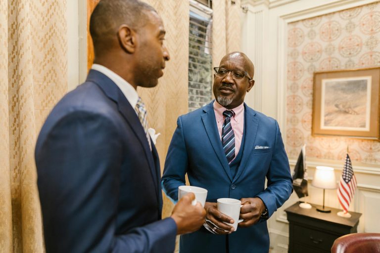 two men talking holding mugs