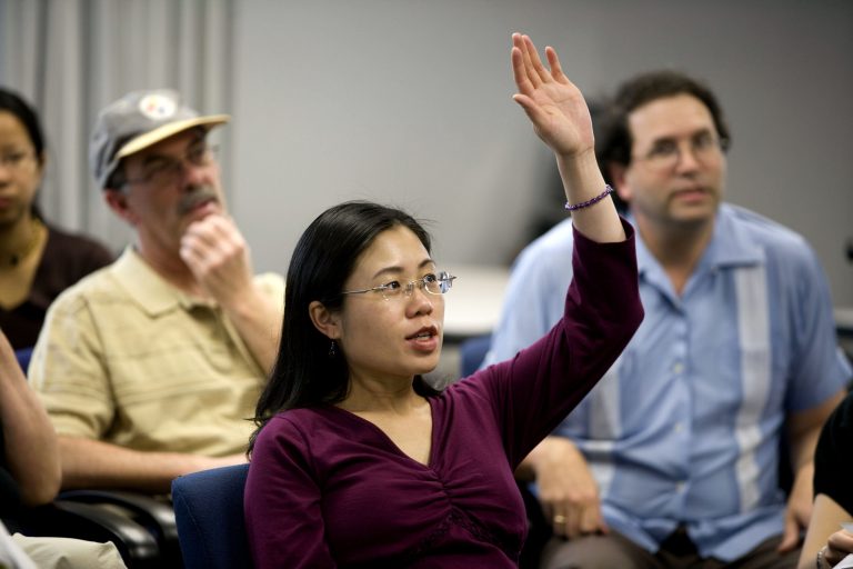 Woman in a class raising hand