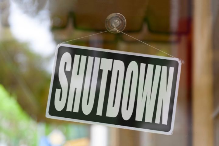 A sign in a storefront that says SHUTDOWN