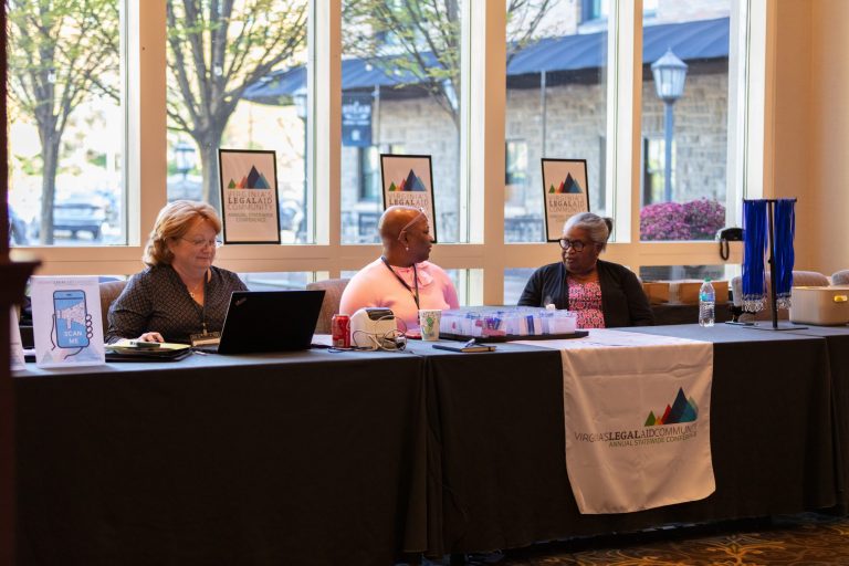 Three women sitting at a registration table at the 2025 Annual Statewide Legal Aid Conference