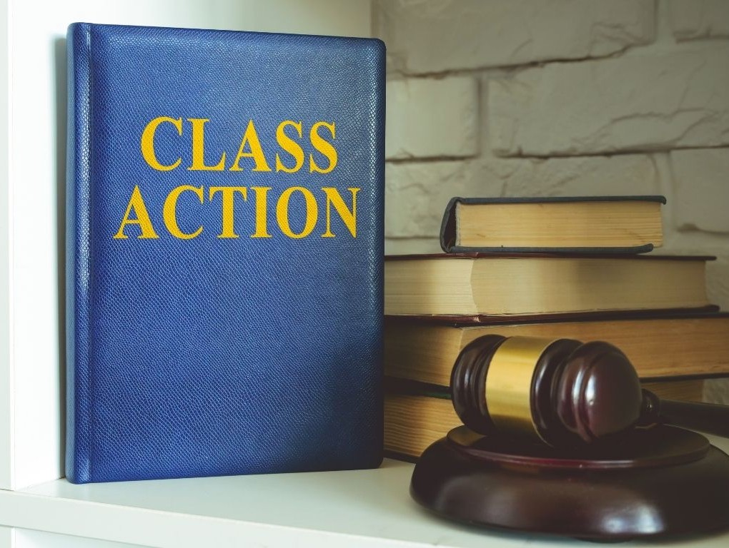 Folder that says "class action" next to a stack of books and gavel