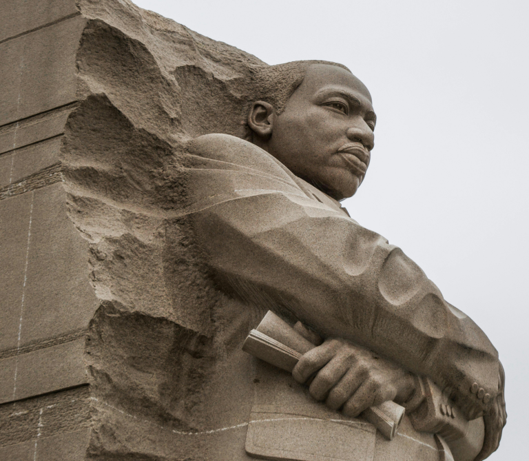 Granite statue of civil rights movement leader Martin Luther King Jr. against overcast sky