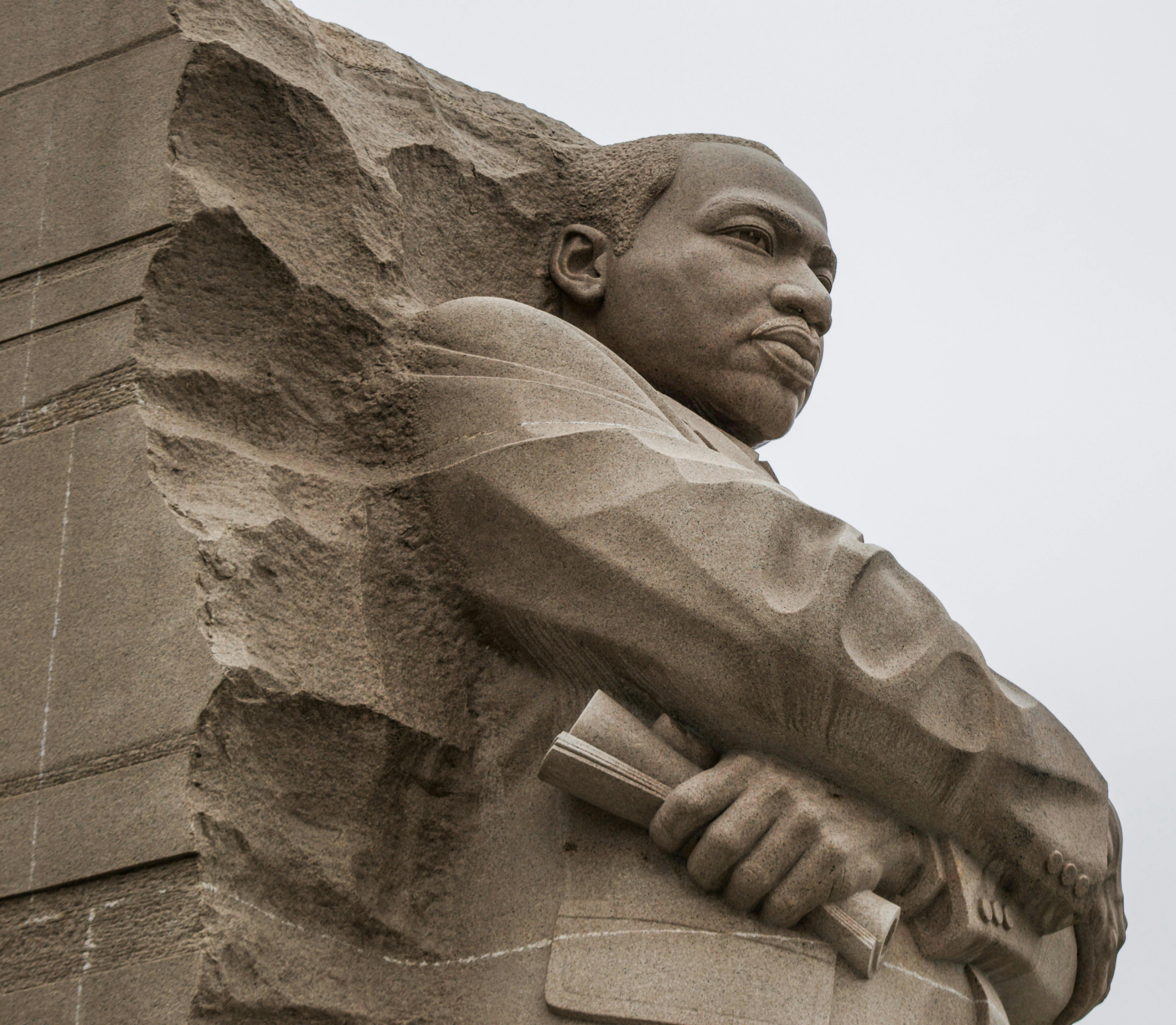 Granite statue of civil rights movement leader Martin Luther King Jr. against overcast sky