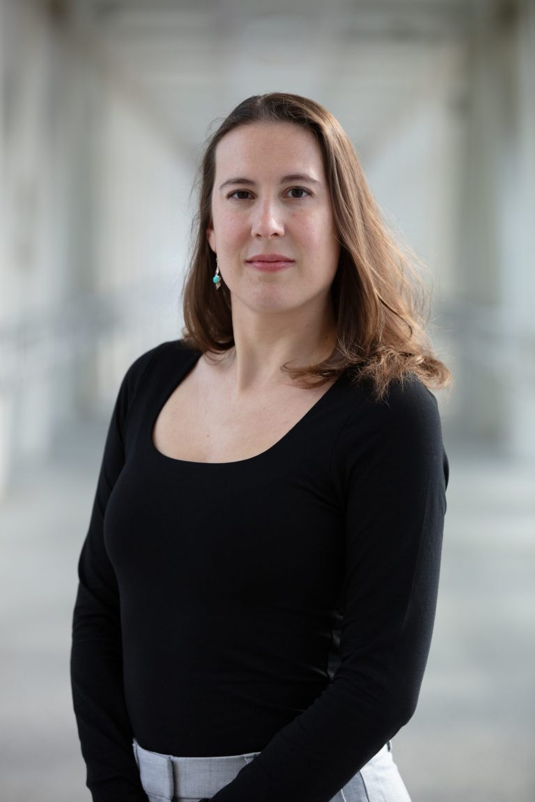 Professional headshot of VPLC employee Eleanor Sullivan, who has long, light brown hair and is wearing a long sleeved black dress shirt.